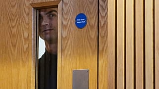 Cristiano Ronaldo espreita pela janela de uma porta durante uma conferência de imprensa em Dublin