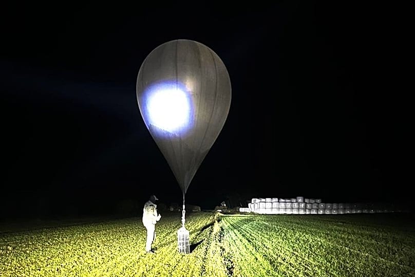 In this undated photo released by the State Border Guard Service, an officer inspects a balloon used to carry cigarettes into Lithuania 