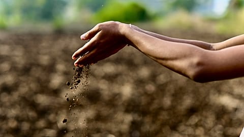 Hands dropping soil onto the Earth.