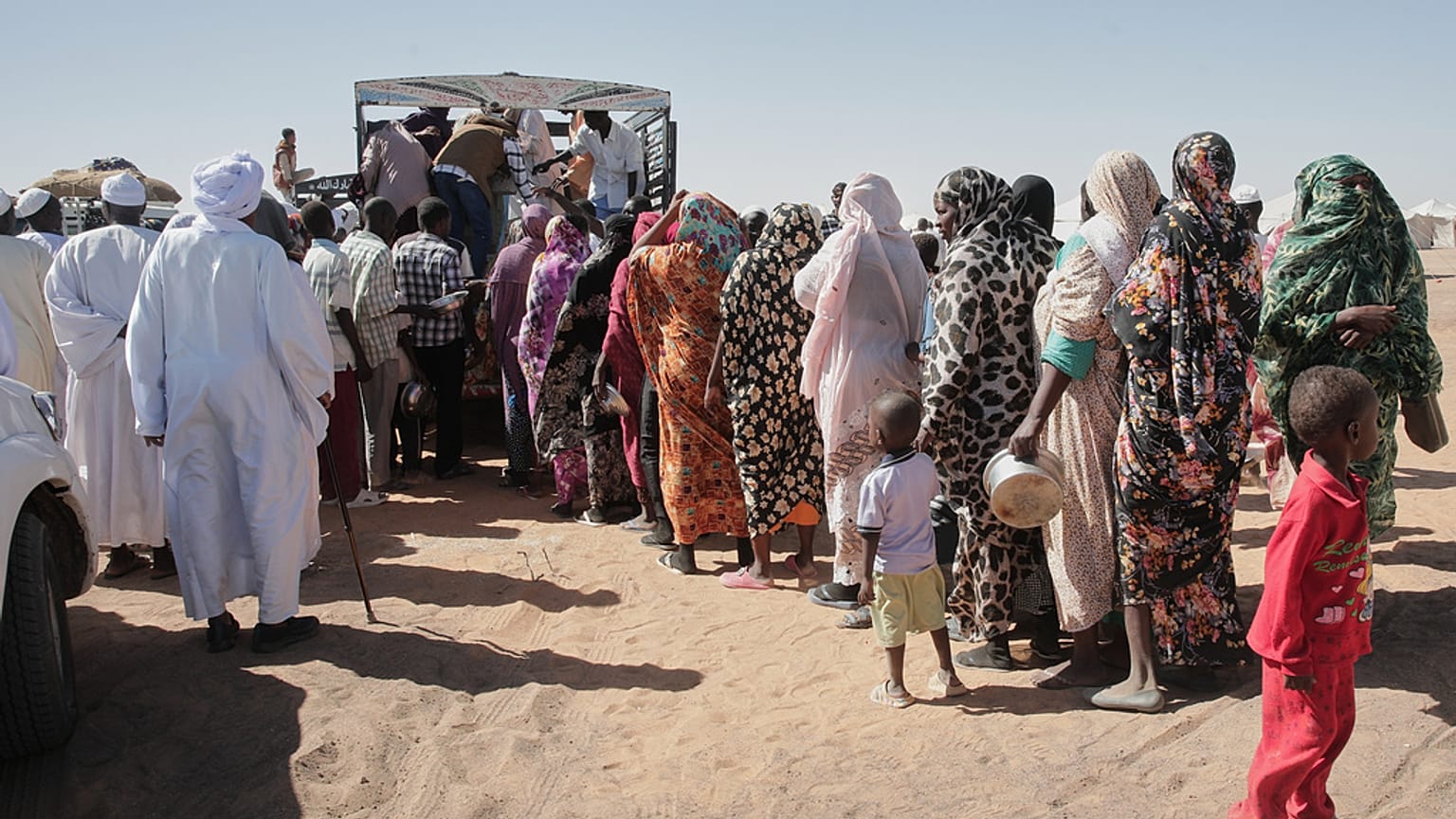 صورة تعبيرية لعائلات سودانية نازحة من الفاشر تصطف للحصول على مساعدات غذائية في مخيم العفاد الذي أُنشئ حديثًا في الدبة