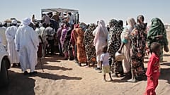صورة تعبيرية لعائلات سودانية نازحة من الفاشر تصطف للحصول على مساعدات غذائية في مخيم العفاد الذي أُنشئ حديثًا في الدبة