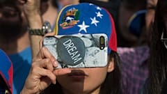ARQUIVO: Uma mulher tira fotografias com um telemóvel com uma capa protetora com a mensagem "sonho" durante um protesto em Madrid, a 19 de abril de 2017.