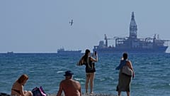 Larnaca'da bir sahilde insanlar, doğal gaz çıkarma çalışmalarını takip ederken, 3 Kasım 2021