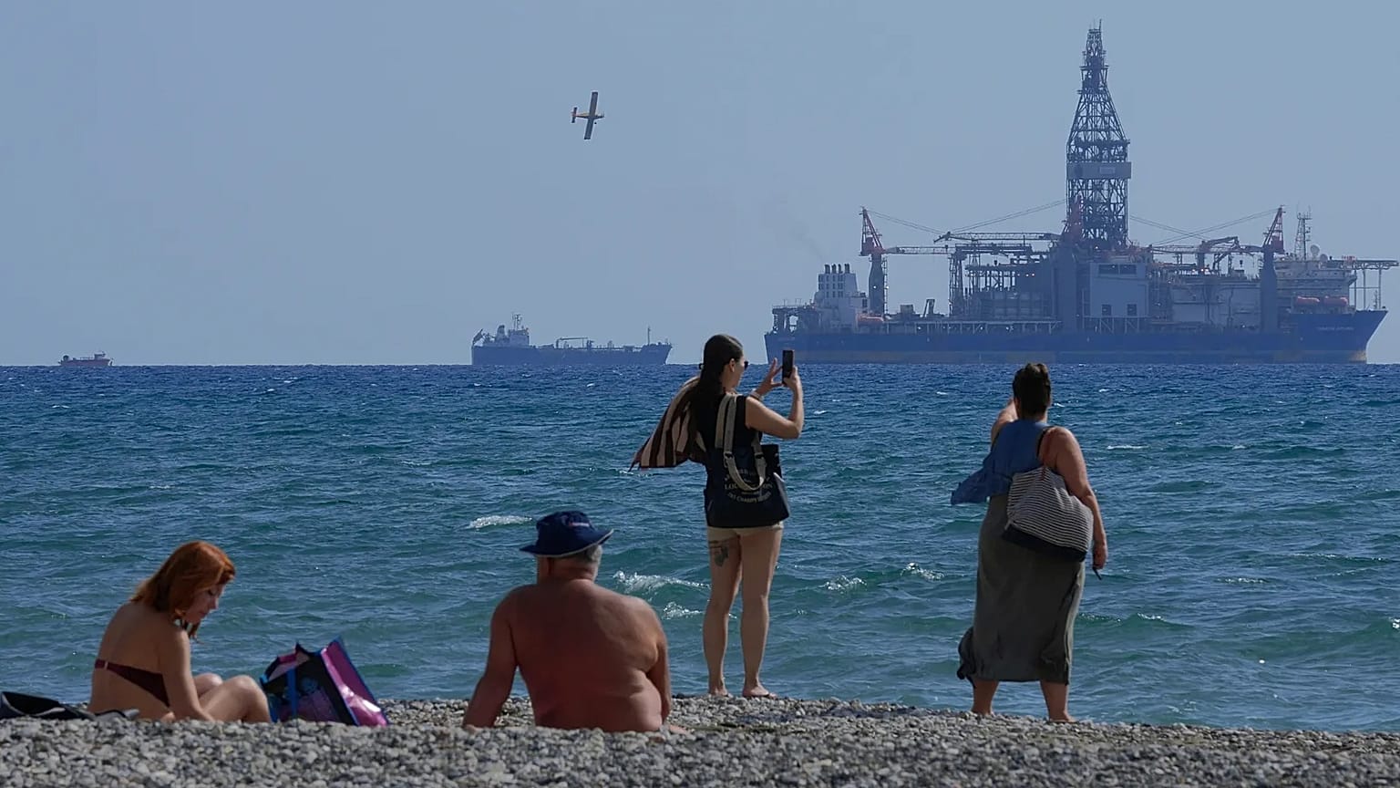 FILE - People on the beach take photos of the 'Tungsten Explorer' drilling ship, in the southern coastal city of Larnaca, Cyprus, Wednesday, Nov. 3, 2021.