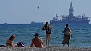 FILE - People on the beach take photos of the 'Tungsten Explorer' drilling ship, in the southern coastal city of Larnaca, Cyprus, Wednesday, Nov. 3, 2021.