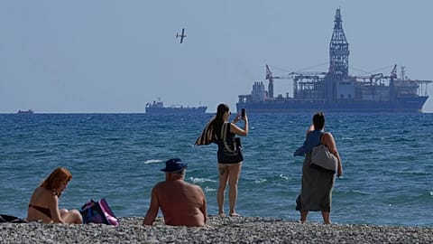 FILE - People on the beach take photos of the 'Tungsten Explorer' drilling ship, in the southern coastal city of Larnaca, Cyprus, Wednesday, Nov. 3, 2021.