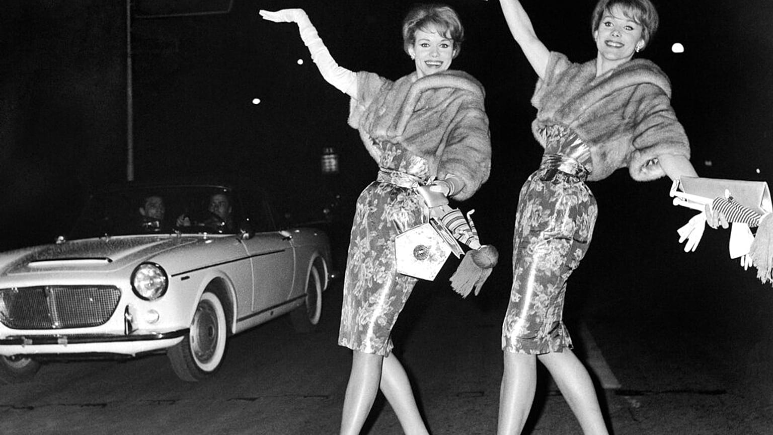 Les jumelles allemandes Alice et Ellen Kessler, danseuses et actrices, à gauche, exécutent une danse dans la rue Via Veneto, très en vogue à Rome, en Italie, le 7 mars 1961.