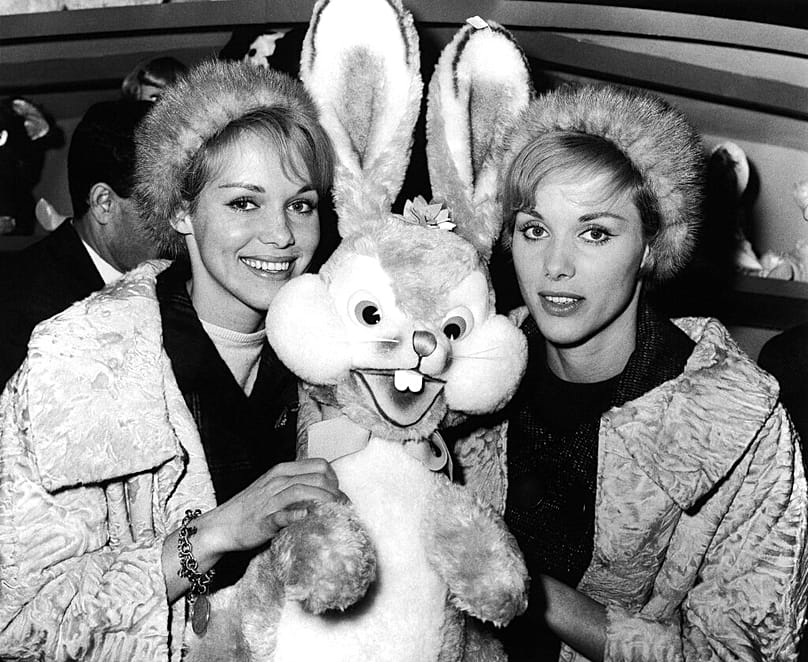 Les jumelles danseuses et actrices allemandes Alice (à droite) et Ellen Kessler tiennent un lapin en peluche dans un magasin de Rome, en Italie, le 18 décembre 1961.