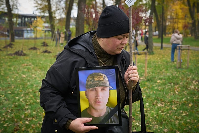 Witwe trauert um ihren im Krieg gefallenen Mann bei einer Aktion, bei der Angehörige Kirschblütenbäume zum Andenken an gefallene Soldaten pflanzen, Kyjiw, Ukraine, 23.10.25