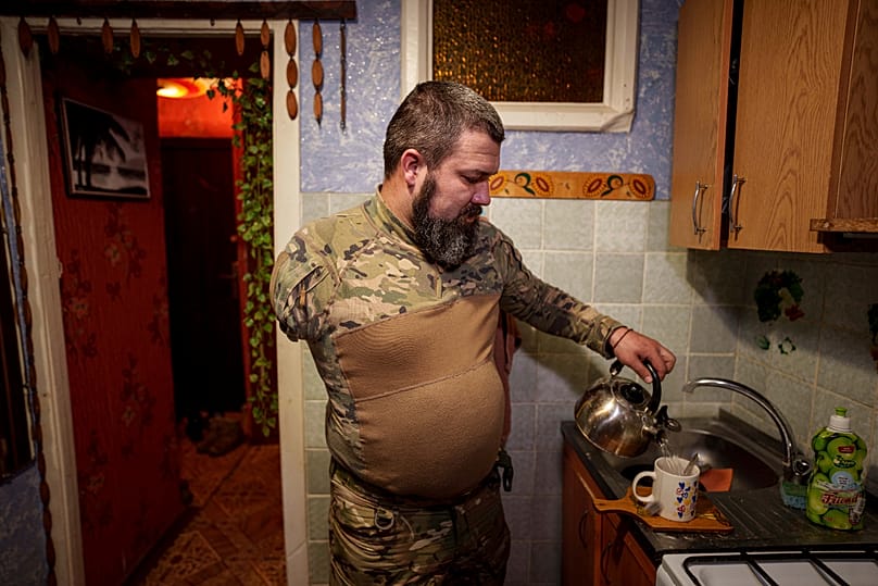 Ukrainischer Soldat der Azov Brigade, der seinen rechten Arm im Krieg verloren hat, macht Tee in seiner Wohnung, Region Donezk, Ukraine, 31.01.2025