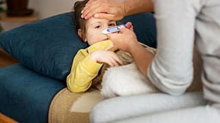 A woman checks a child's temperature.