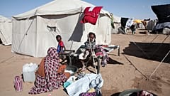 امرأة سودانية نزحت من الفاشر تغسل ملابسها خارج خيمة عائلتها بينما يجلس الأطفال بالقرب من مخيم العفاد المنشأ حديثا في الضبعة بولاية شمال السودان ، الأحد نوفمبر. 16, 2025