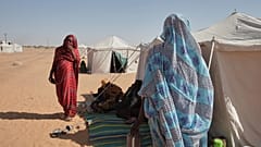 نادرة محمد أحمد، على اليسار، تقف خارج خيمتها في مخيم الأفضح الذي تم إنشاؤه حديثًا في الدبة بولاية شمال السودان، يوم الاثنين 17 نوفمبر 2025. (صورة أسوشيتد برس/ مروان علي)