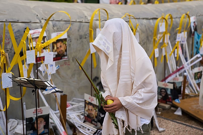 رجل يرتدي شال الصلاة، يصلي ويحمل العناصر الأربعة المستخدمة كرمز في عيد العرش اليهودي، في ساحة تعرف بساحة الرهائن 10 أكتوبر 2025