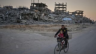 رجل يقود دراجته برفقة طفلته في شارع متضرر بمخيم الشاطئ - مدينة غزة، الثلاثاء، 18 نوفمبر 2025.
