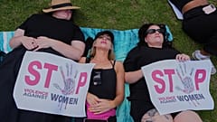 Teilnehmende liegen am Boden, halten Schilder: „Stoppt Gewalt gegen Frauen“. Protest gegen genderbasierte Gewalt in Johannesburg, Südafrika, 21. Nov. 2025
