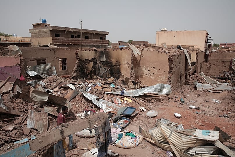 A man walks by a house hit in recent fighting in Khartoum, 25 April, 2023 