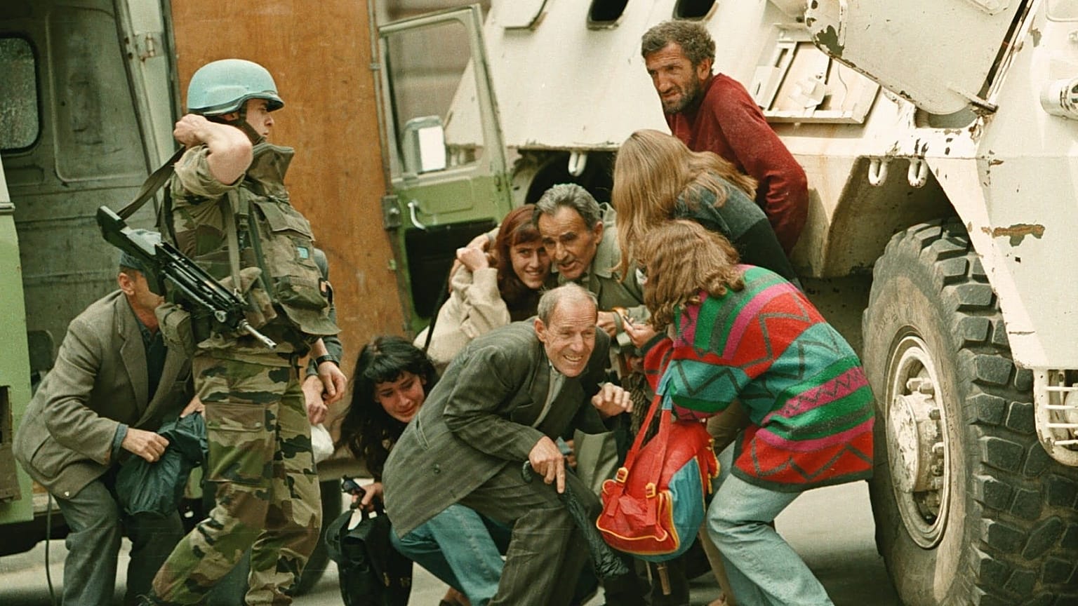 Szarajevóiak bujkálnak az orvlövészek golyói elől egy ENSZ-páncélkocsi mögött, 1995. június 8-án