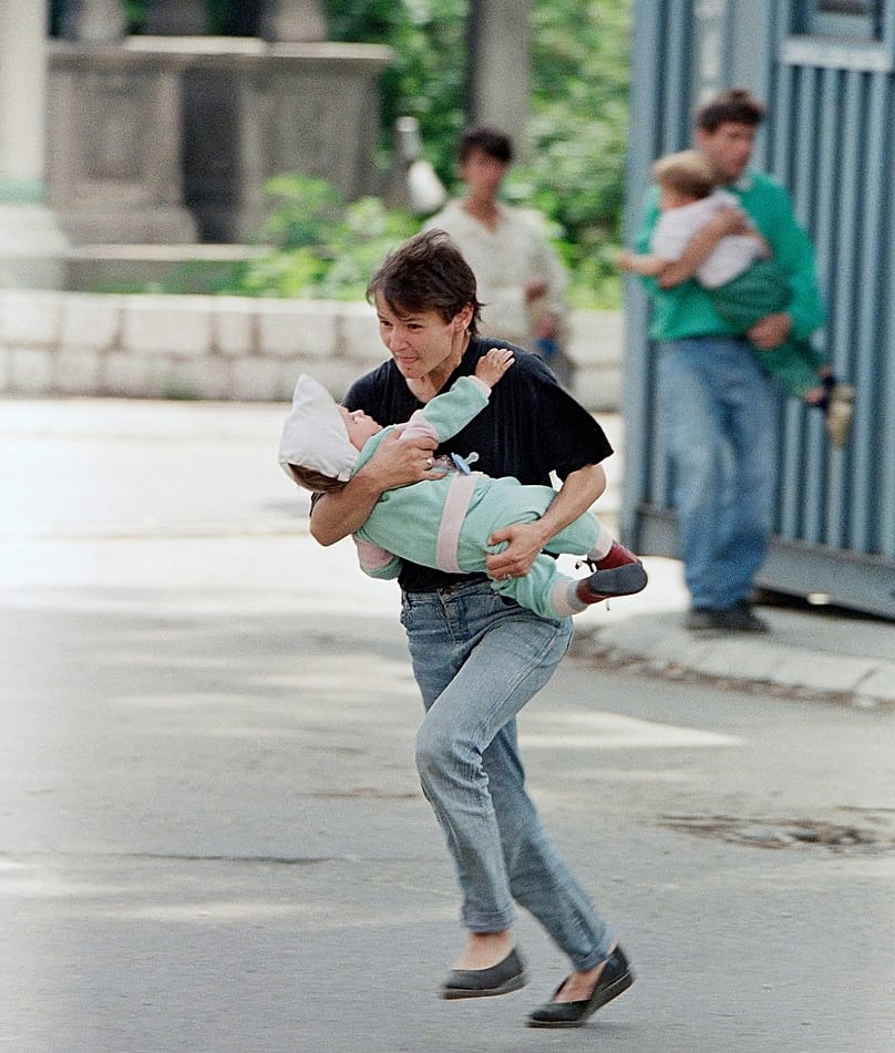 Egy, a gyermekét átölelő szarajevói anya fut át az orvlövészek kereszttüzében tartott útkereszteződésen, mögöttük egy apa figyeli, sikerrel járnak-e, 1995. június 6-án
