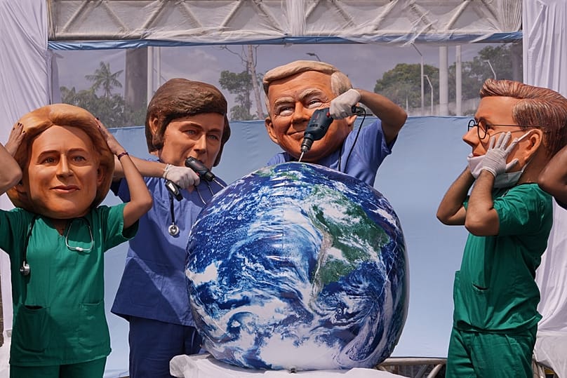 Arjantin Devlet Başkanı Milei (ortada solda) ve ABD Başkanı Trump (ortada sağda) kılığına giren göstericiler, Dünya üzerinde delik açıyormuş gibi yapıyor, 20 Kasım 2025.