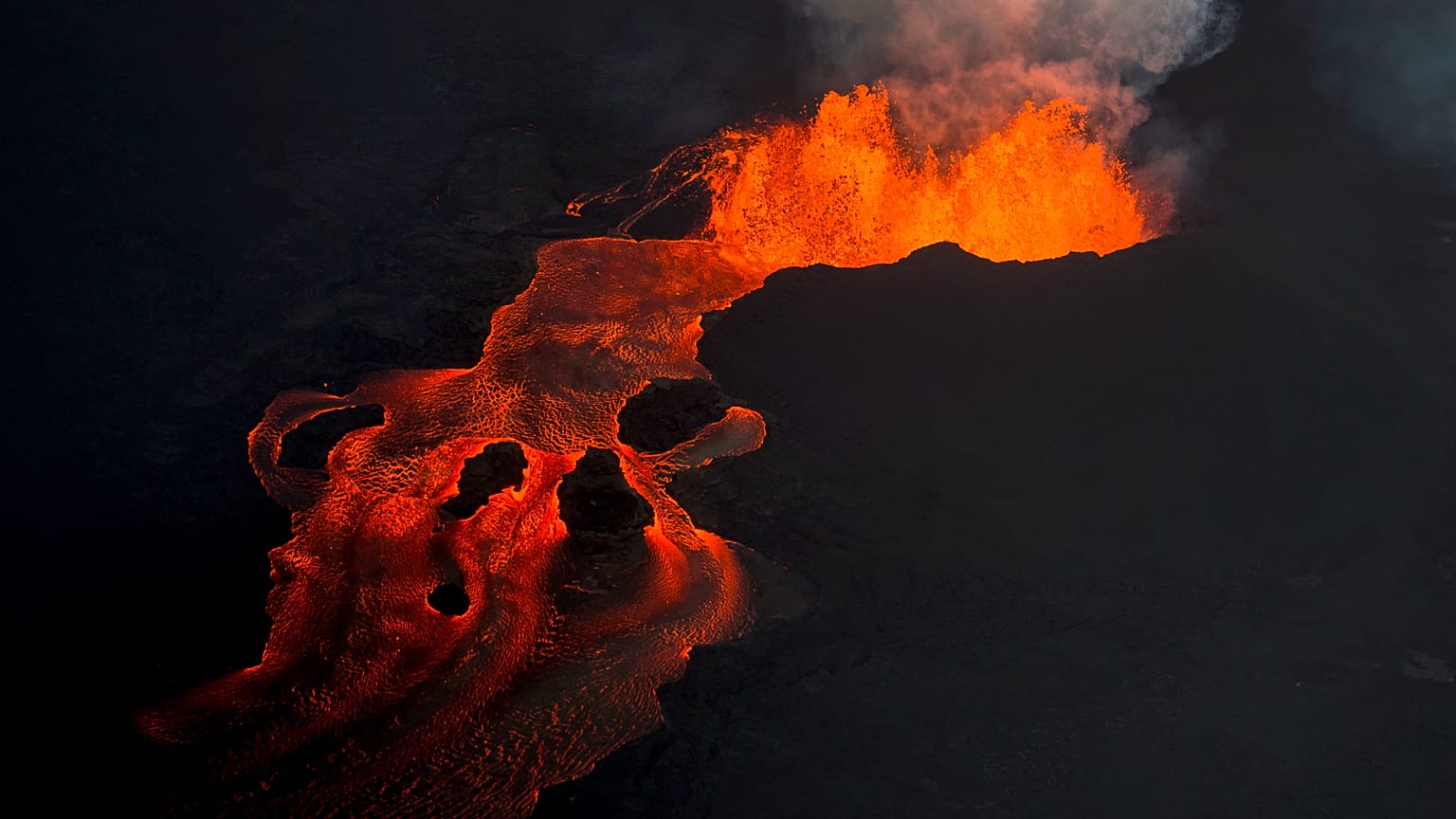 In this June 10, 2018 photo, lava from the Kilauea volcano continues to erupt from a fissure and forms a river of lava flowing down to Kapoho in Pahoa, Hawaii.