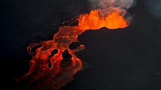 In this June 10, 2018 photo, lava from the Kilauea volcano continues to erupt from a fissure and forms a river of lava flowing down to Kapoho in Pahoa, Hawaii.