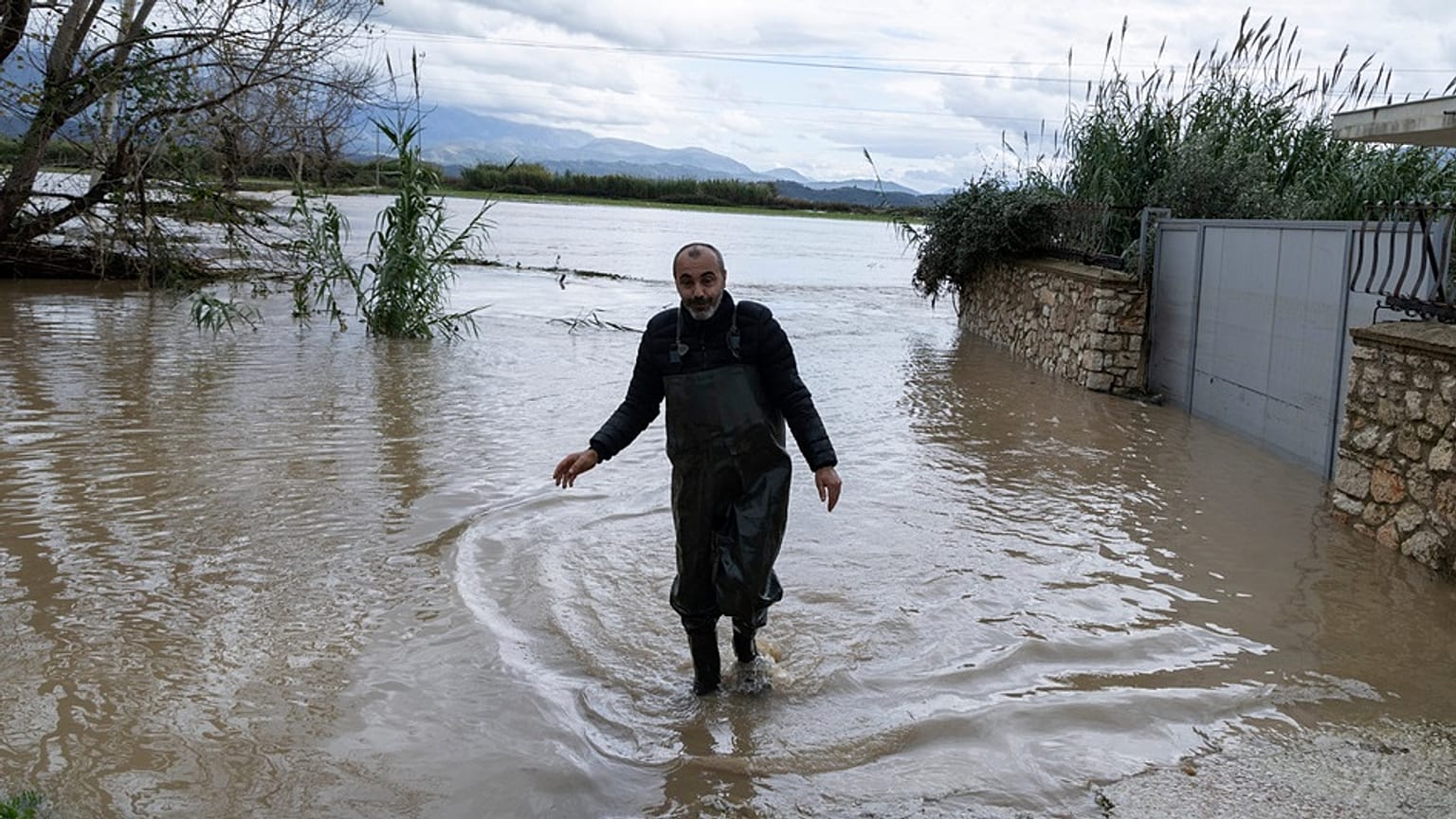 Egy férfi sétál egy elárasztott területen Cuke városában, Saranda közelében, Dél-Albániában, 2025. november 22-én