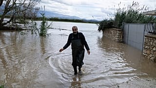 Egy férfi sétál egy elárasztott területen Cuke városában, Saranda közelében, Dél-Albániában, 2025. november 22-én