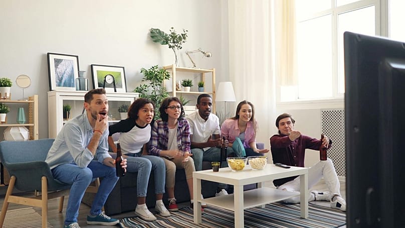  مجموعة من الأصدقاء يشاهدون التلفاز بحماس.