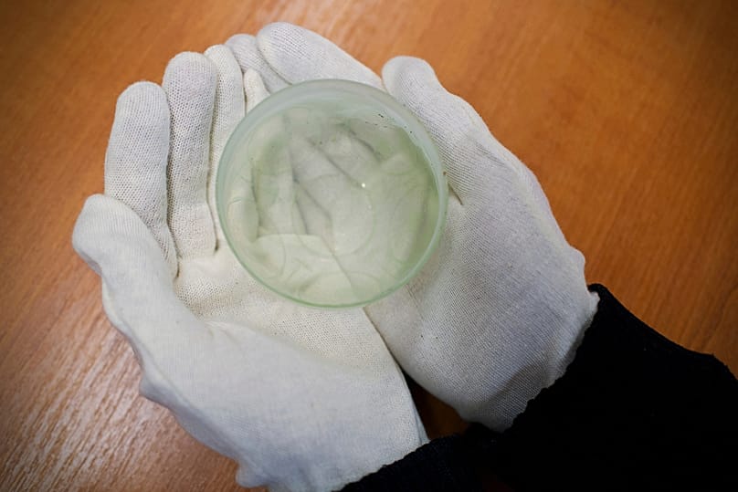 An archaeologist holds a glass jar found in an intact Roman sarcophagus, Wednesday, Nov. 19, 2025 in Budapest, Hungary. 