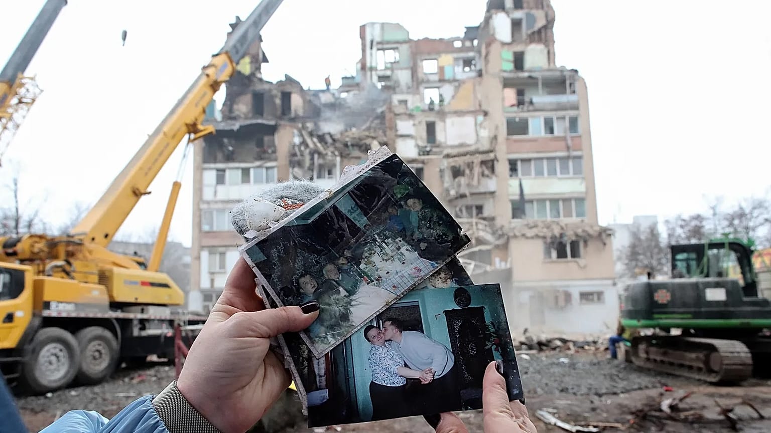A woman looks on family photographs in front of a residential building which was heavily damaged by a Russian strike on Ternopil, Ukraine, Nov. 21, 2025