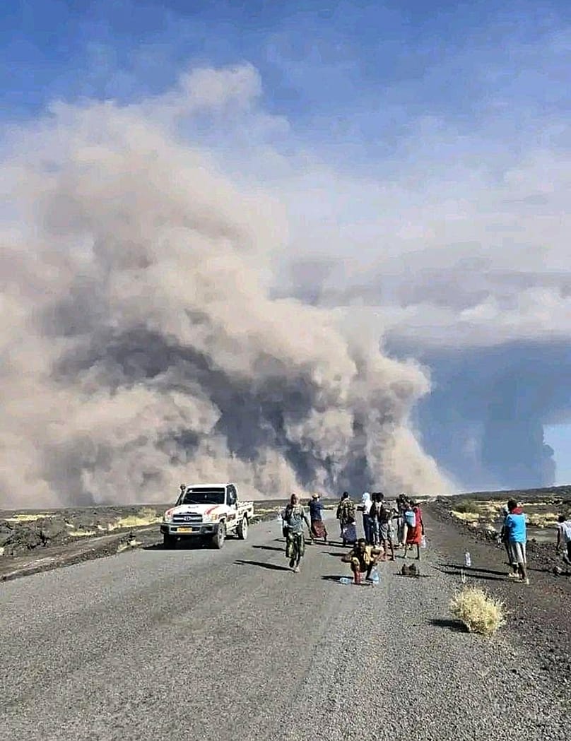 People watch ash billow from an eruption of the long-dormant Hayli Gubbi Volcano in Ethiopia's Afar region, 23 November 2025