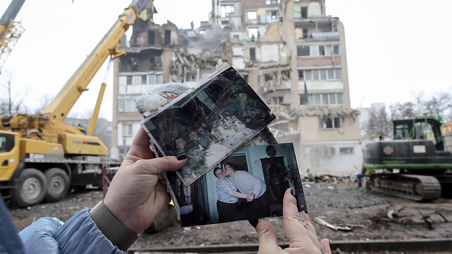 Une femme regarde des photos de famille devant un immeuble résidentiel qui a été fortement endommagé par une frappe russe sur Ternopil, en Ukraine, le 21 novembre 2025