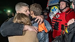 Ein Mann umarmt seine Kinder. Sie reagieren auf den Tod ihrer Mutter, die bei einem russischen Luftangriff getötet wurde.