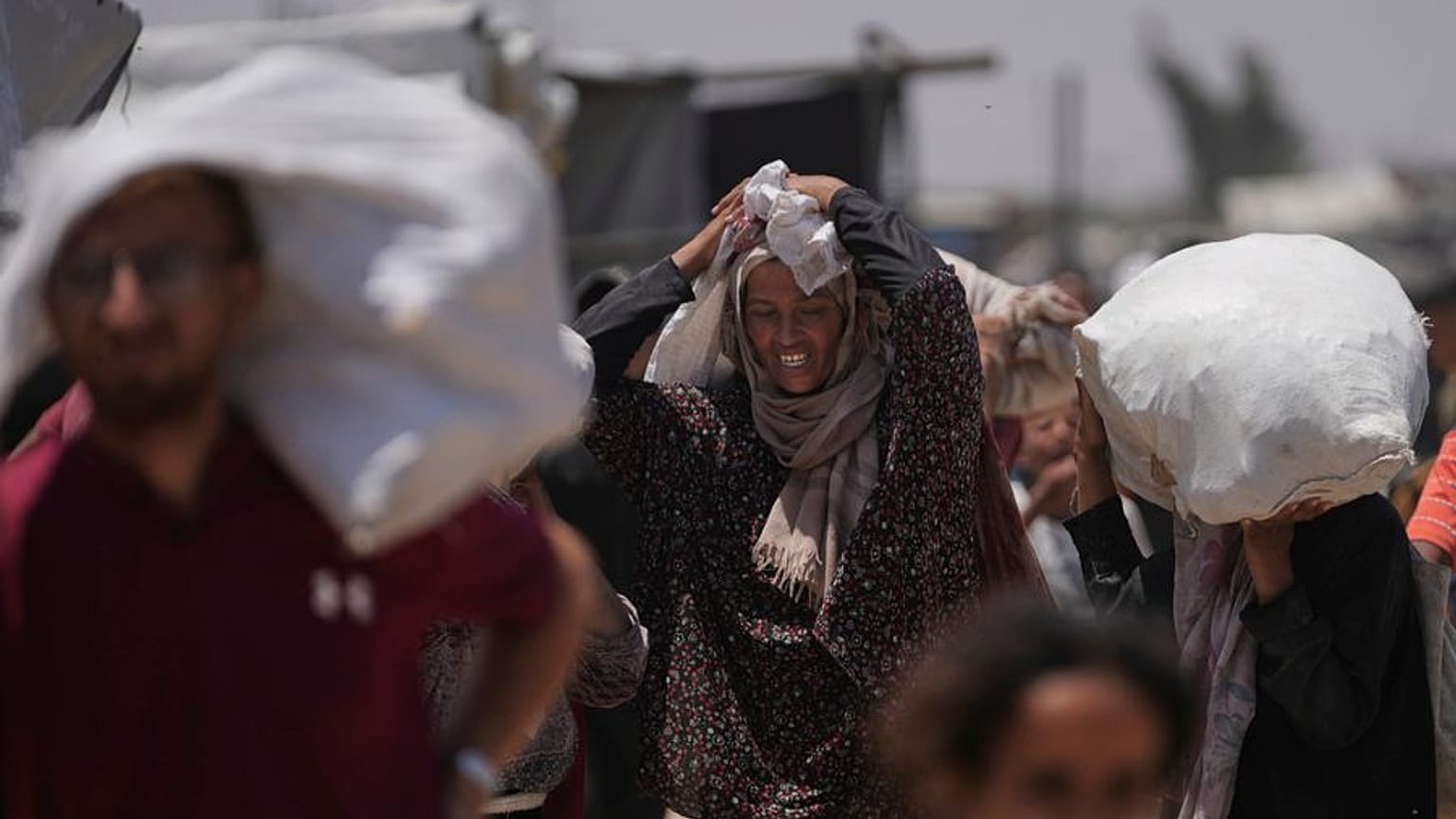 فلسطينيون يحملون أكياسًا تحتوي على مساعدات غذائية وإنسانية قدمتها مؤسسة غزة الإنسانية، رفح، جنوب قطاع غزة، يوم الاثنين 16 يونيو/حزيران 2025. 