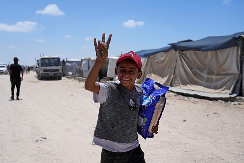 طفل فلسطيني يبتسم للكاميرا وهو يحمل كيس أرز سلمته مؤسسة غزة الإنسانية جنوب قطاع غزة، يوم الأربعاء 28 مايو 2025. 