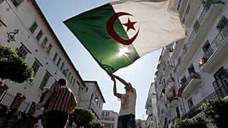 يُلوّح رجل بالعلم الجزائري خلال مظاهرة في العاصمة الجزائر، يوم الجمعة 27 سبتمبر/أيلول 2019.