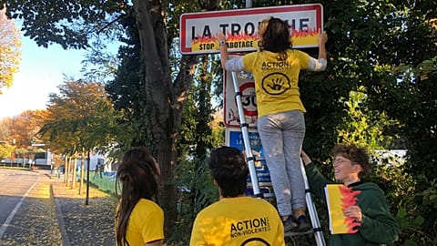 Activists glue fake flames onto road signs in France.
