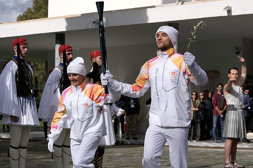 A kétszeres olimpiai bajnok sífutó olasz Stefania Belmondo és a görög evezős olimpiai bajnok Petrosz Gajdatzisz az olimpiai lánggal 2024. november 26-án.