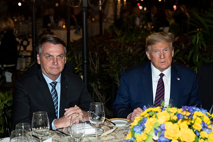 FILE - President Donald Trump is seated before a dinner with Brazilian President Jair Bolsonaro, left, at Mar-a-Lago in Palm Beach, Florida, March 7, 2020