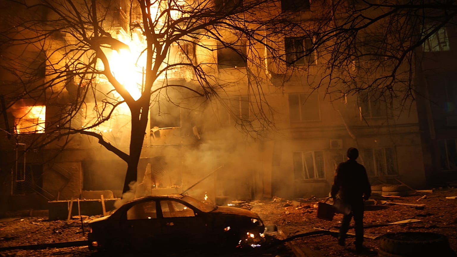 رجل يسير أمام مبنى سكني محترق بعد هجوم روسي على زابوريزهيا، أوكرانيا، الأربعاء 26 نوفمبر/تشرين الثاني 2025. 