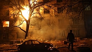 رجل يسير أمام مبنى سكني مشتعل بعد هجوم روسي على زاباروجيا في أوكرانيا، الأربعاء 26 تشرين الثاني/نوفمبر 2025.