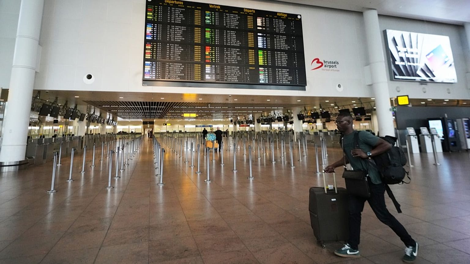 FILE: A man walks through an empty terminal with a departure board of cancelled flights at Brussels International Airport in Zaventem, 14 October 2025