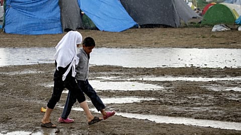 Gyerekek sétálnak egy sáros mezőn az észak-görögországi Idomeni határállomáson, Görögországban 2016. április 25-én, hétfőn.