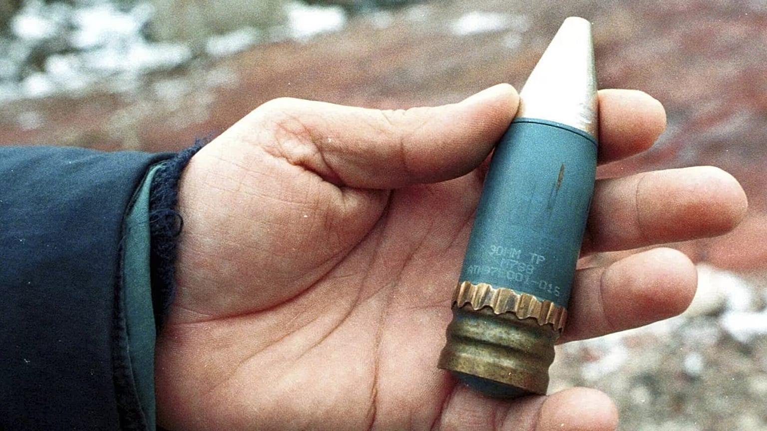 A member of a radiation team holds a 30mm armor-piercing shell containing depleted uranium.