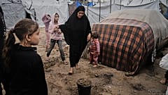 فلسطينيون نازحون يسيرون في الوحل داخل مخيم خيام مؤقت بعد هطول أمطار غزيرة في مدينة غزة يوم الثلاثاء 25 نوفمبر 2025. (تصوير: جيهاد الشريف/أسوشيتد برس)