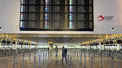 A person walks through the empty hall with a departure board of cancelled flights at Brussels International Airport 