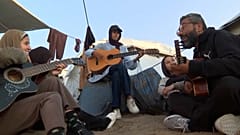 Ο Αχμέτ Αμπού Αμσά, καθηγητής μουσικής, παίζει κιθάρα και τραγουδά μαζί με μαθητές στη Λωρίδα της Γάζας