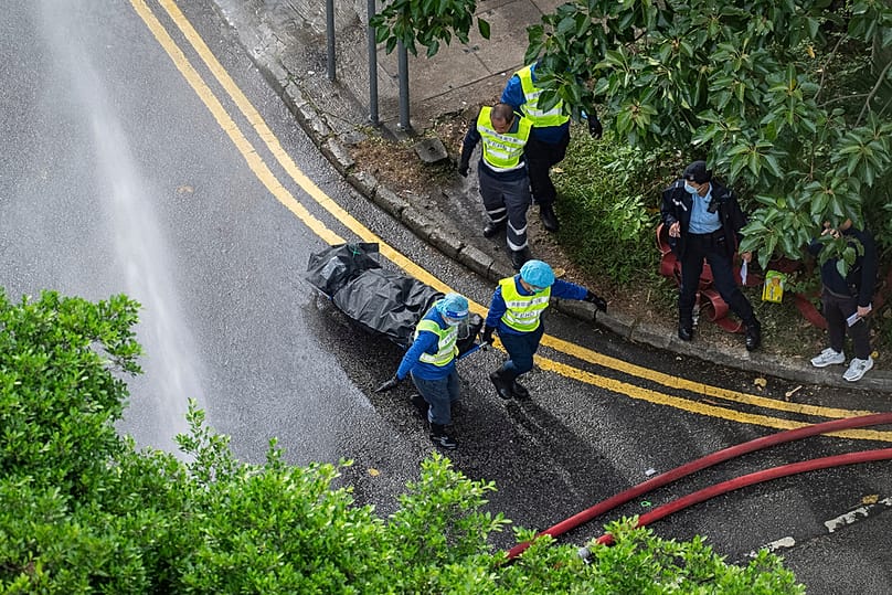 Workers remove a body from a fire which broke out on Wednesday at a residential estate in the Tai Po district of Hong Kong's New Territories, Thursday, Nov. 27, 2025
