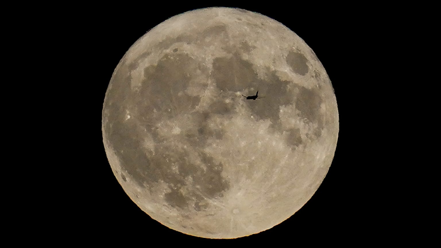 Ein Flugzeug fliegt am 30. August 2023 vor dem Mond in Chicago vorbei.